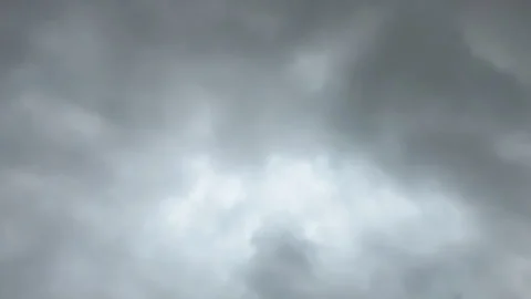 A dramatic, low-key image of a brooding, dark cloudy sky, featuring four tiny Video stock 318729448