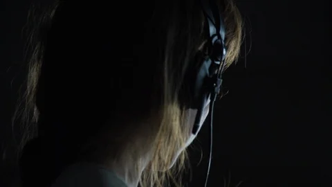 Dramatic low key lighting of close up shot of female musician in headphones Stock Footage 98760164