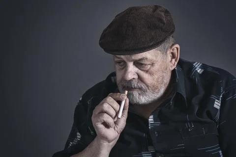 Dramatic low key portrait of hesitating Caucasian senior man with cigarette Stock Photos
