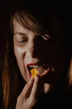 Dramatic low-key portrait of a person with red lipstick eating. Stock Photos