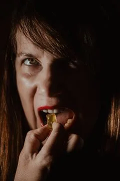 Dramatic low-key portrait of a person with red lipstick eating. Stock Photos