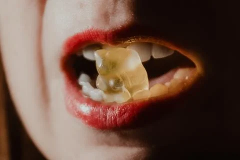 Dramatic low-key portrait of a person with red lipstick eating. Stock Photos