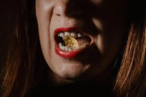 Dramatic low-key portrait of a person with red lipstick eating. Stock Photos