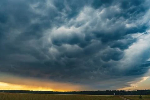 Dramatic mammatus storm clouds forming above a rural landscape during sunset Stock Photos