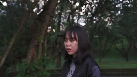 Dramatic medium shot of scared, young Asian girl turning around worriedly Stock Footage 270137187