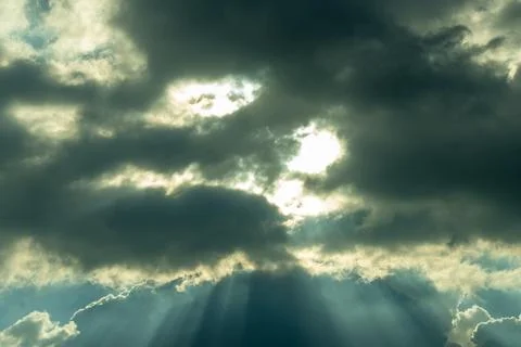 A dramatic, moody sky with dark stormy clouds powerful sun rays Stock Photos