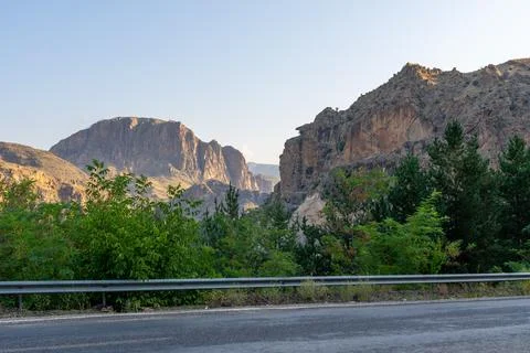 Dramatic mountain canyon with a lush green valley and winding road below Stock Photos