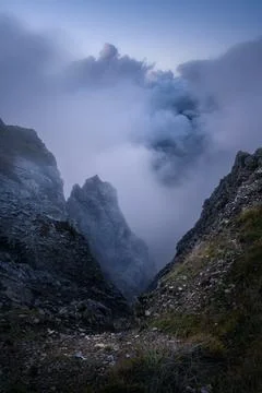 Dramatic mountain gorge with rocky cliffs in slouds Stock Photos