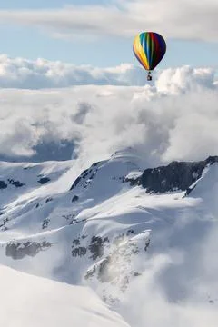 Dramatic Mountain Landscape covered in clouds and Hot Air Balloon Flying Stock Illustration