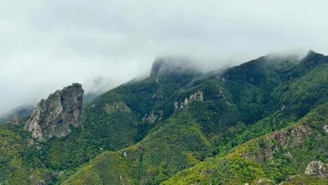 A Dramatic Mountain Landscape Elegantly Surrounded by Fluffy Clouds and Lush Stock Photos