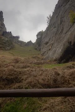Dramatic mountain landscape with large rock faces and grassy valley. Stock Photos