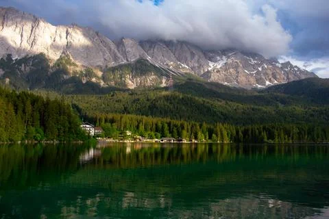Dramatic Mountain Landscape over Lake and Green Forest Stock Photos