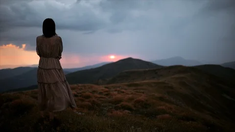 Dramatic mountain landscape with rain on the horizon. Young woman in a long Stock Footage 118587796
