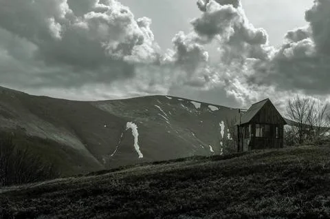 Dramatic mountain landscape with rustic cabin and storm clouds Foto stock