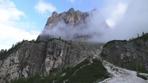 Dramatic mountain peak in the Dolomites covered by clouds under a blue sky in Stockbeeldmateriaal 318514733