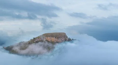 Dramatic mountain peak emerges from atmospheric clouds at sunrise Stock Photos