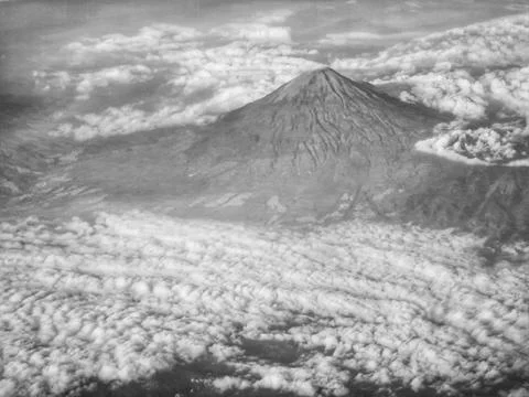 Dramatic mountain peak rises above a sea of clouds in monochrome tones Perfec Stock Photos