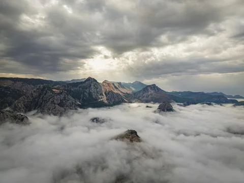 Dramatic mountain peaks rising above a thick sea of clouds Stock Photos