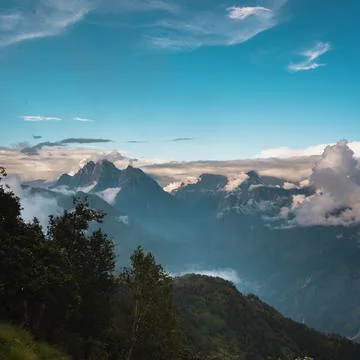 Dramatic mountain range bathed in soft sunrise light, with clouds swirling ar Stock Photos