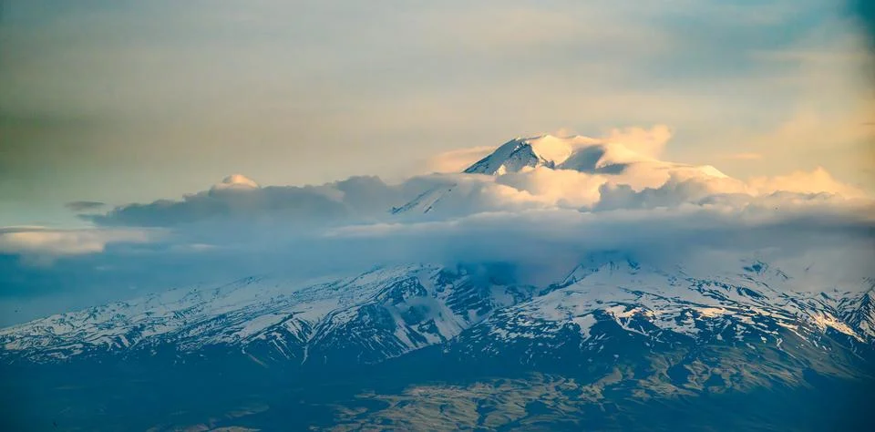 Dramatic mountain range covered in snow under cloudy sky Stock Photos