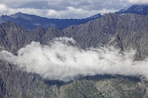 Dramatic mountain range with a sea of clouds rolling over the peaks. Stock Photos
