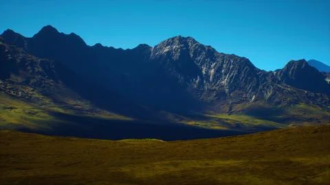 Dramatic mountain range under a clear blue sky during daylight hours Stock Illustration