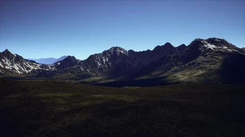 Dramatic mountain range under a clear blue sky during daylight hours Stock Illustration