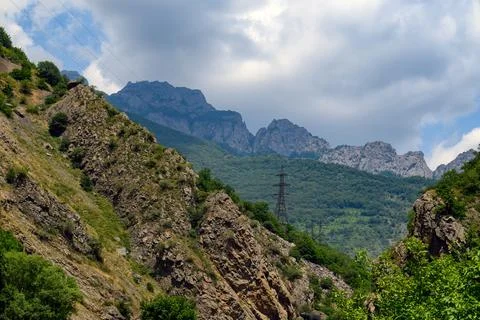 Dramatic mountain scene with lush greenery and cloudy sky Stock Photos