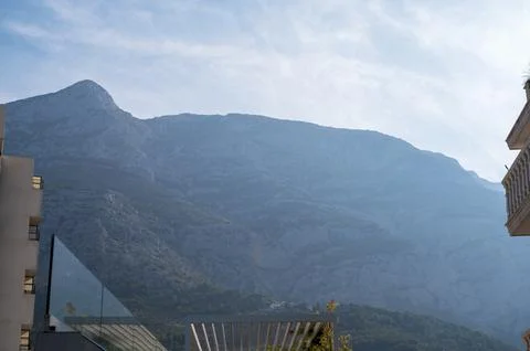 Dramatic mountain scenery viewed above a modern sunlit resort terrace with Stock Photos