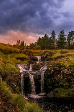 Dramatic mountain waterfall under stormy sky at dusk Photos