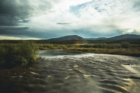 Dramatic nature scene of a raging river and dramatic clouds Stock Photos