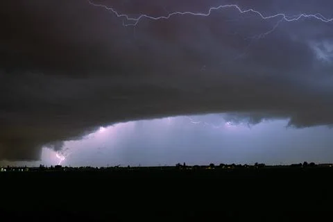 Dramatic night lightning storm with low shelf cloud and distant rural horizon Stock Photos