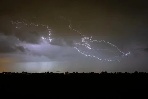 Dramatic night lightning streaks across a stormy sky above a dark horizon Fotos Stock