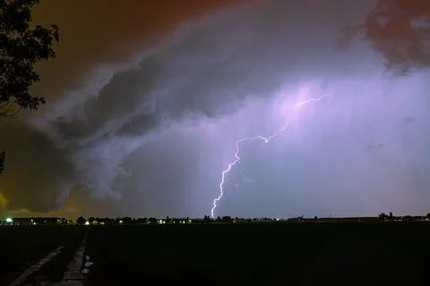 Dramatic night lightning strike under rolling storm clouds over plain landscape Foto stock