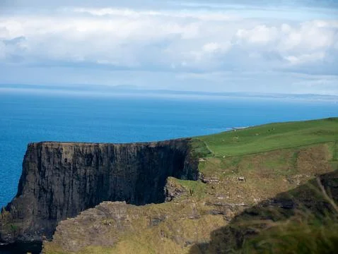 Dramatic ocean cliff with green coastline Photos