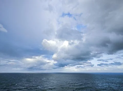 Dramatic Ocean Horizon Beneath a Vast Cloudy Sky with Soft Sunlight Breaking  Stock Photos
