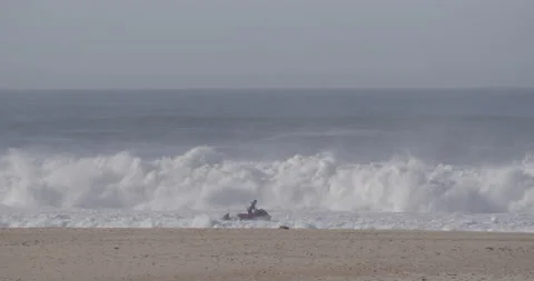 Dramatic ocean with professional surfer riding big waves on jet ski in Nazare Stock Footage 160782584