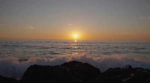 Dramatic ocean sunset. Burning sky and shining golden waves hit rocks. Sunset Stock-Fotos