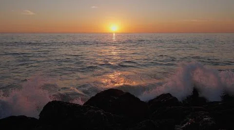 Dramatic ocean sunset. Burning sky and shining golden waves hit rocks. Sunset Stock Photos