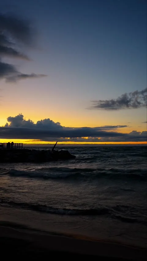 Dramatic Ocean Sunset with Dark Waves and Silhouetted Stone Pier Video stock 331968473