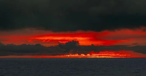 Dramatic ocean sunset with fiery red clouds and dark stormy sky Photos