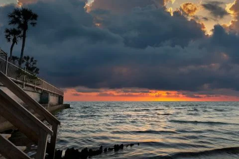 Dramatic Ocean Sunset with Sea Wall and Palm Trees in Foreground Stock Photos