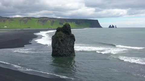 Dramatic ocean waves crash against a tall sea stack on black sand beach wit.. 스톡 동영상 337806425