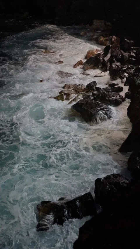 Dramatic ocean waves crash on the rocky shoreline at dusk, creating an Stock Footage 308864185