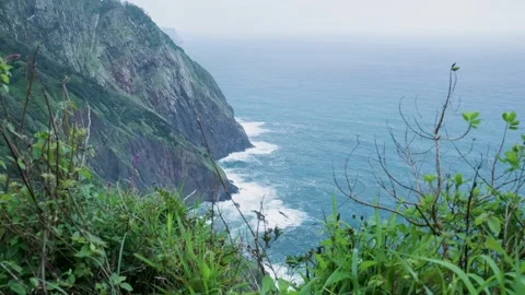 Dramatic ocean waves crashing against steep green cliffs Видео 333696043