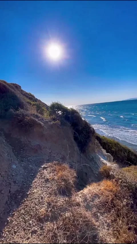 Dramatic Ocean Waves Crashing Against Sea Cliffs with Bright Sun Stock Footage 345346443
