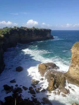 Dramatic ocean waves pound the rocky coast below the natural rock arch. Stock Photos