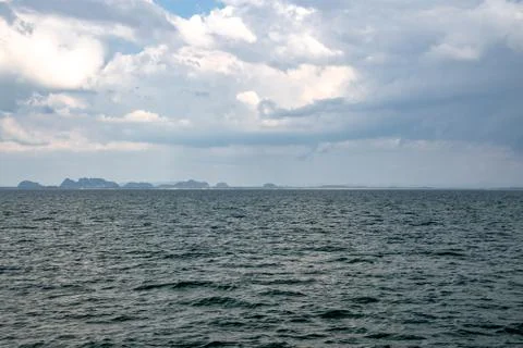 Dramatic ocean waves with sunrays peeking out of clouds off the coast of Thai Stock Photos