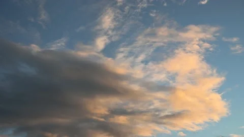 Dramatic orange and grey summer storm clouds move slowly through a bright blue s Stock Footage 139691711