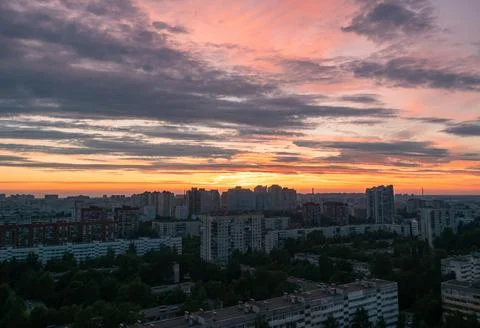 Dramatic orange and pink clouds illuminate a vast urban skyline at sunset Foto stock